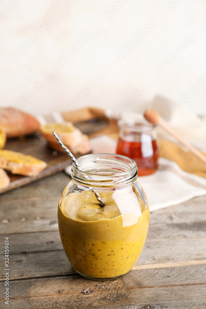 Jar of tasty honey mustard sauce on wooden table