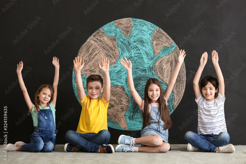 Little children and drawing of planet on dark background. Earth Day celebration