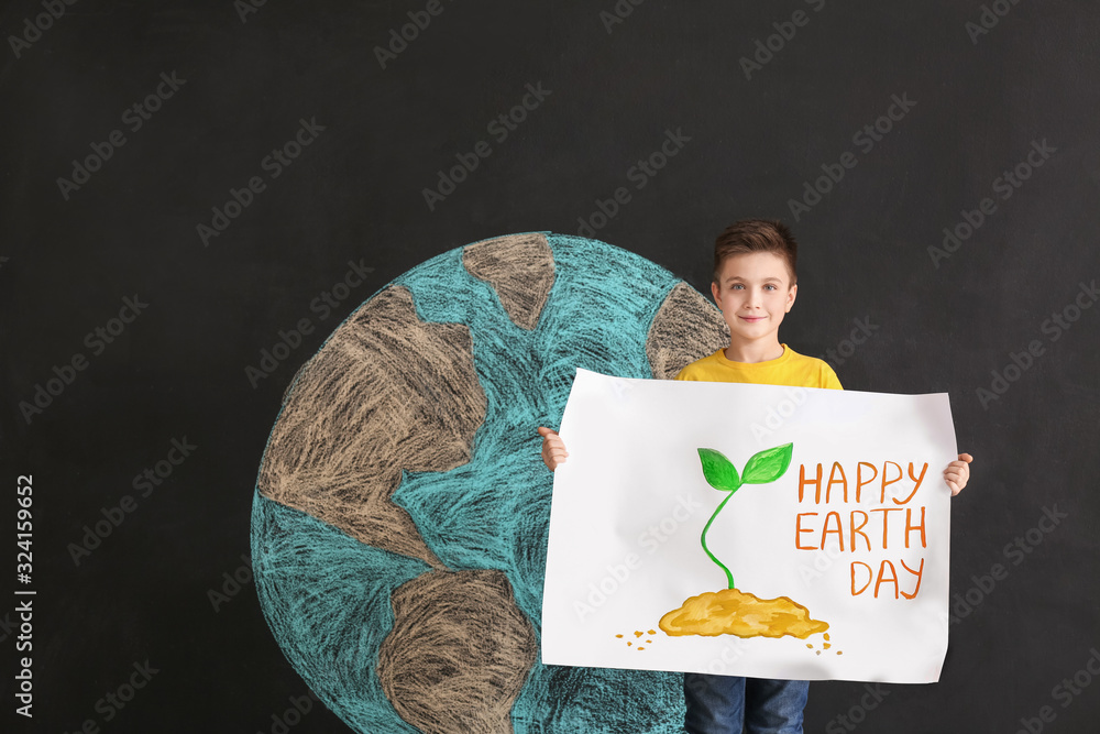 Little boy with poster and drawing of planet on dark background. Earth Day celebration