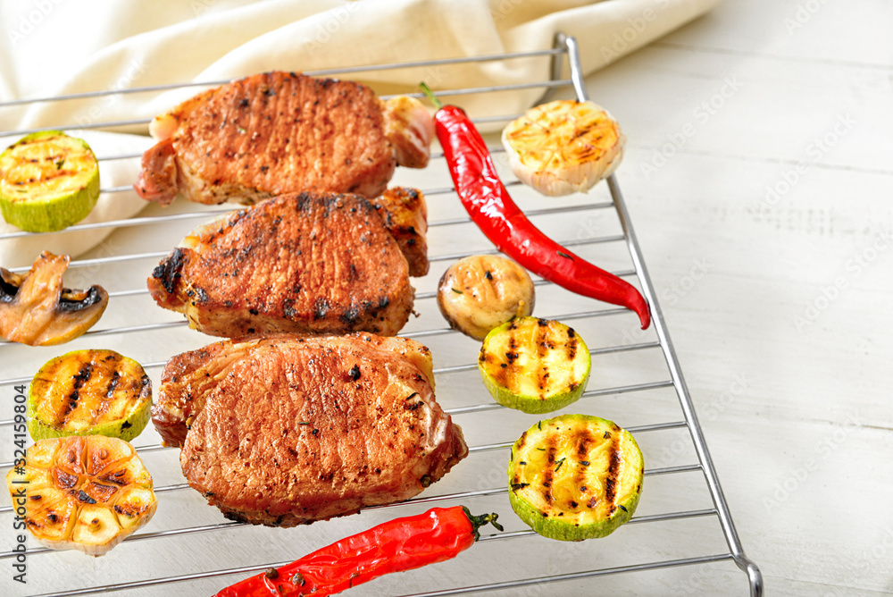 Cooling rack with cooked pork steaks and vegetables on table