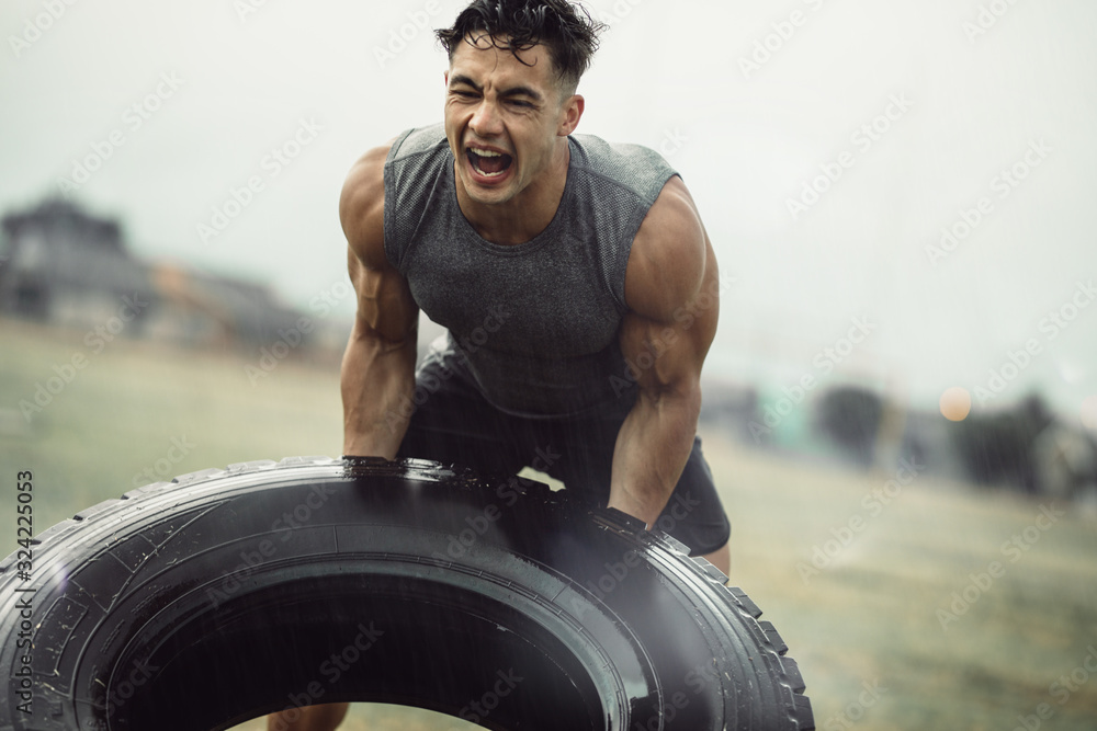 Strong sportsman doing a tire flip exercise