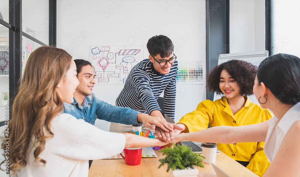 Young Asian people stacking hands for teamwork concept