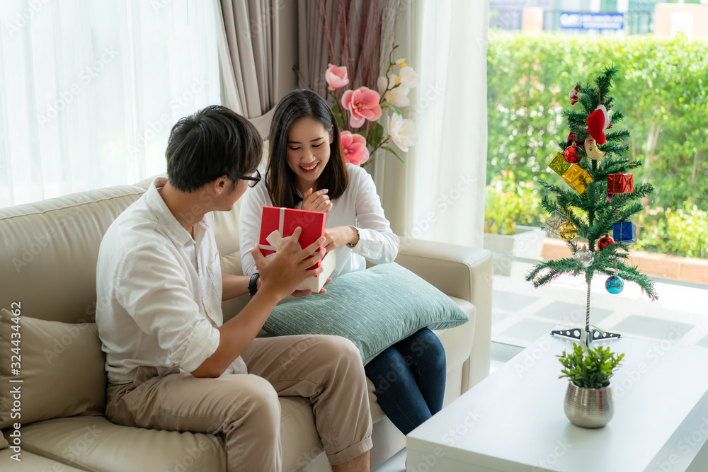 Asian man give the woman a red gift box in which there is a bottle of perfume. The woman was picked 