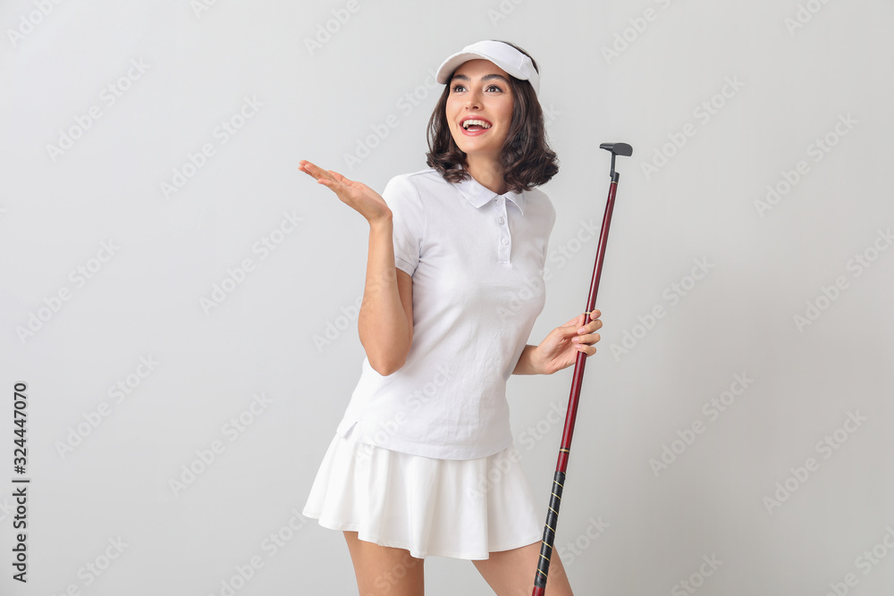 Beautiful female golfer on light background