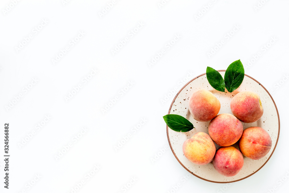 Summer fruits. Ripe red peaches on plate on white table top-down copy space