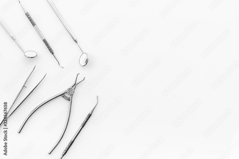 Stomatological tools on dentists desk on white background top-down pattern frame space for text