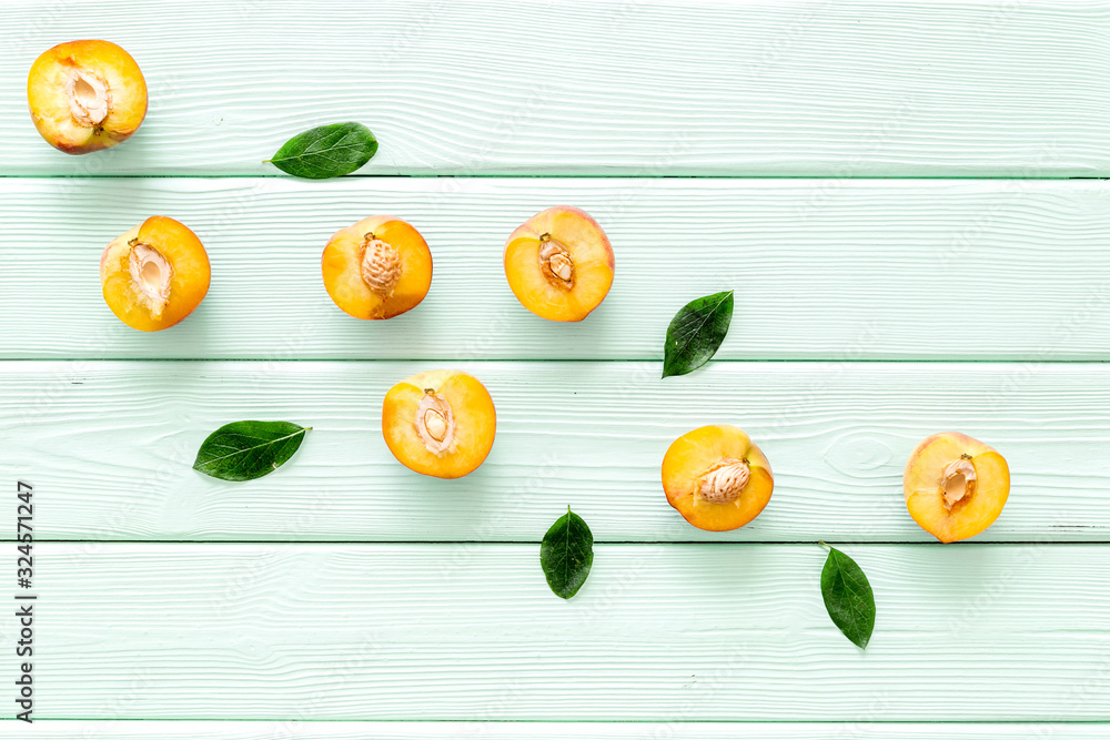 Peach slices and leaves pattern on green wooden background top-down copy space