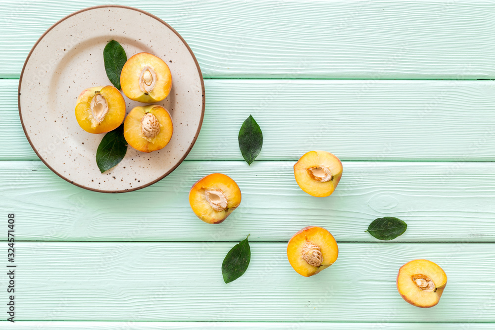 Peaches pattern with plate and leaves on green wooden table top-down copy space