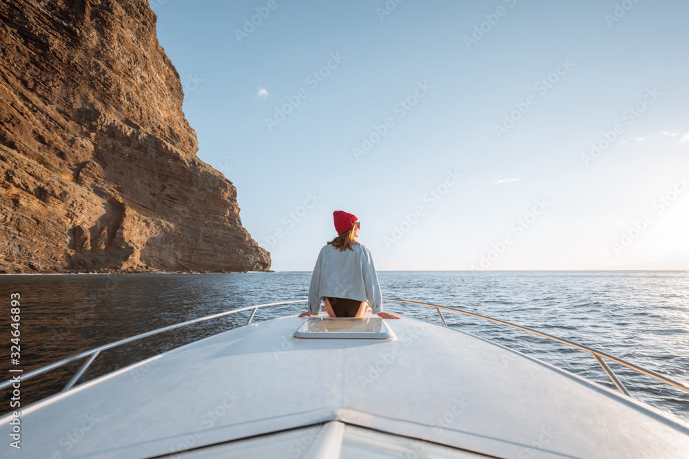 戴着红帽子的女人享受着海上航行，坐在游艇机头上，航行时呼吸急促