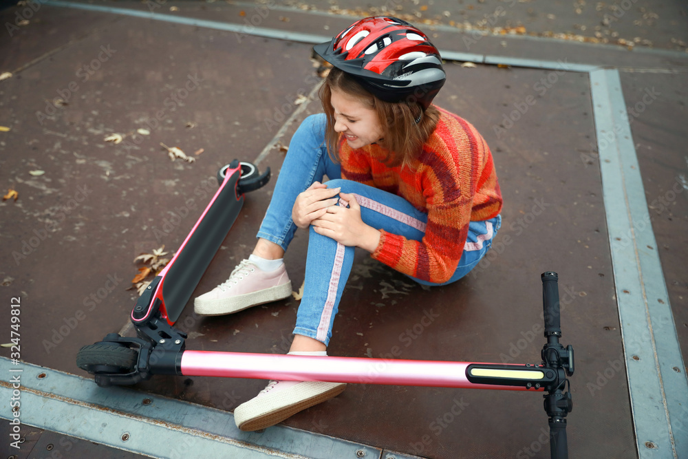 Teenage girl fallen off her kick scooter outdoors