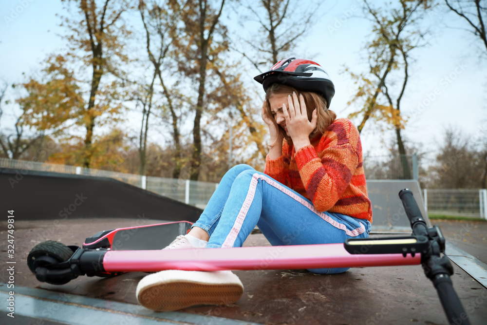 Teenage girl fallen off her kick scooter outdoors