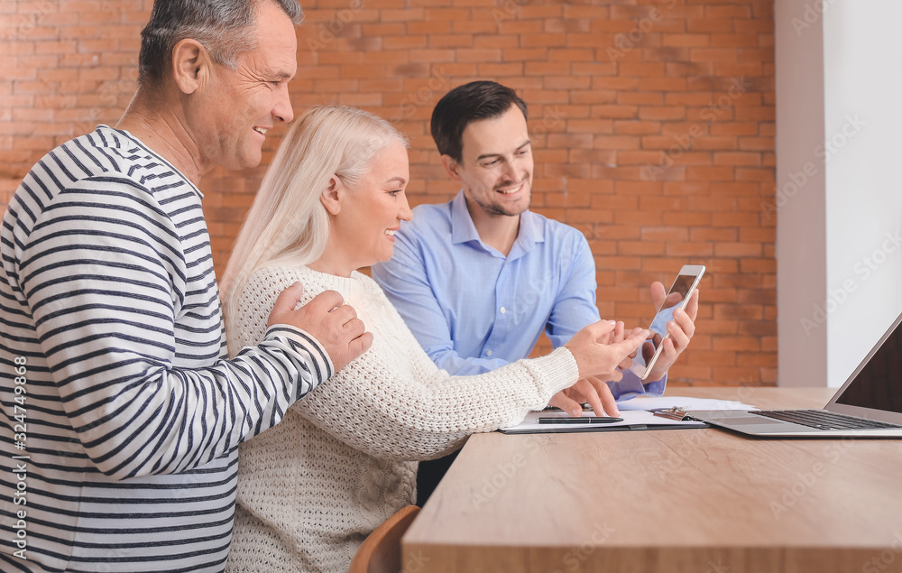 Male real estate agent working with mature couple indoors