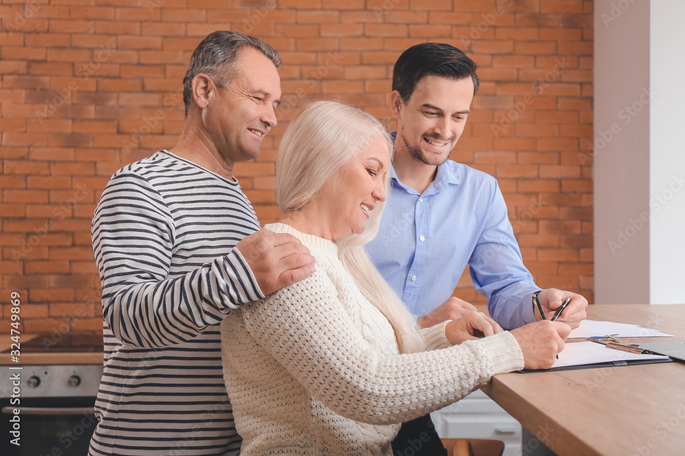 Mature couple signing a sale and purchase contract in their new house