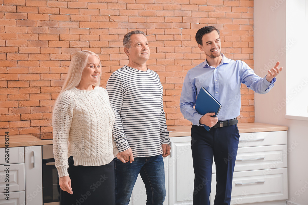 Male real estate agent showing mature couple a new house