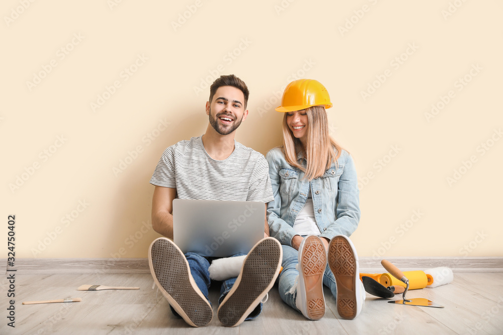 Young couple with laptop planning repair of their new apartment