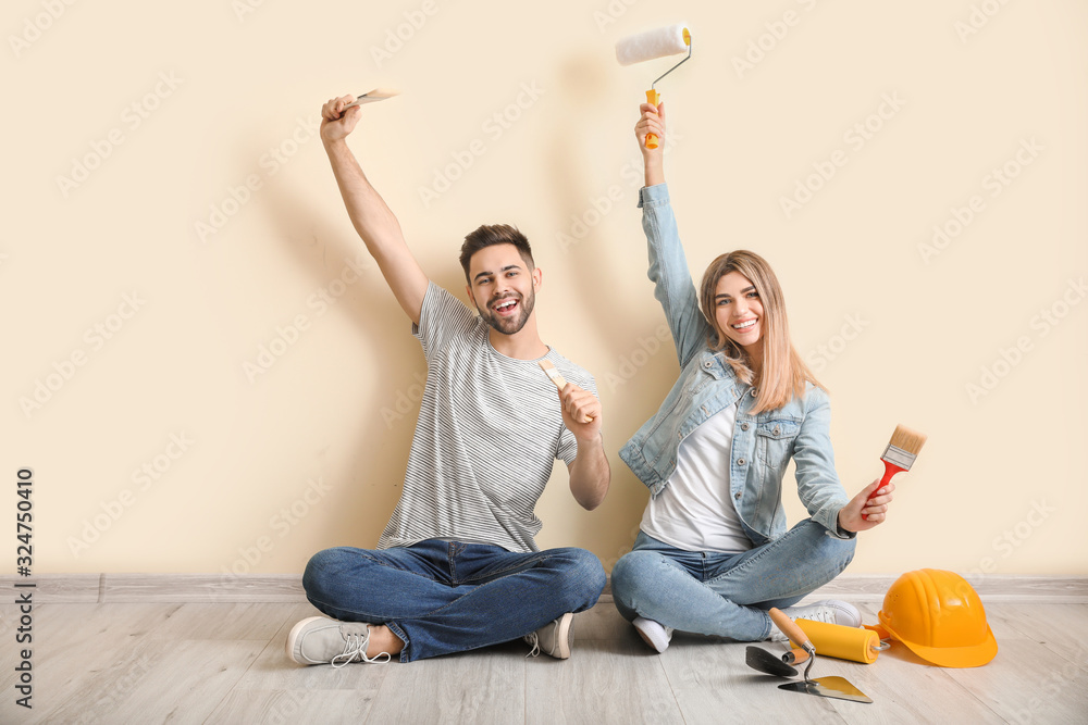 Young couple with tools resting during repair in new apartment