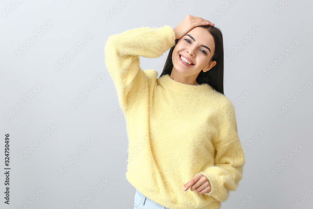 Beautiful young woman in warm sweater on light background