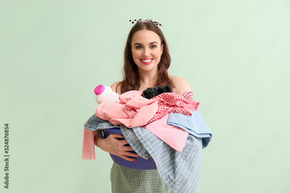 Funny housewife with laundry on color background