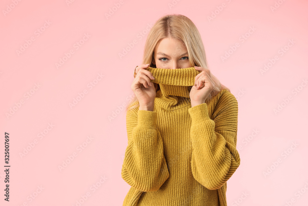 Young woman in warm sweater on color background