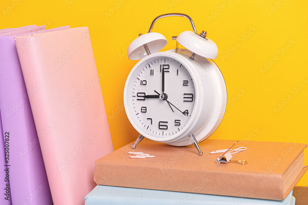 Set of school supplies and clock on color background