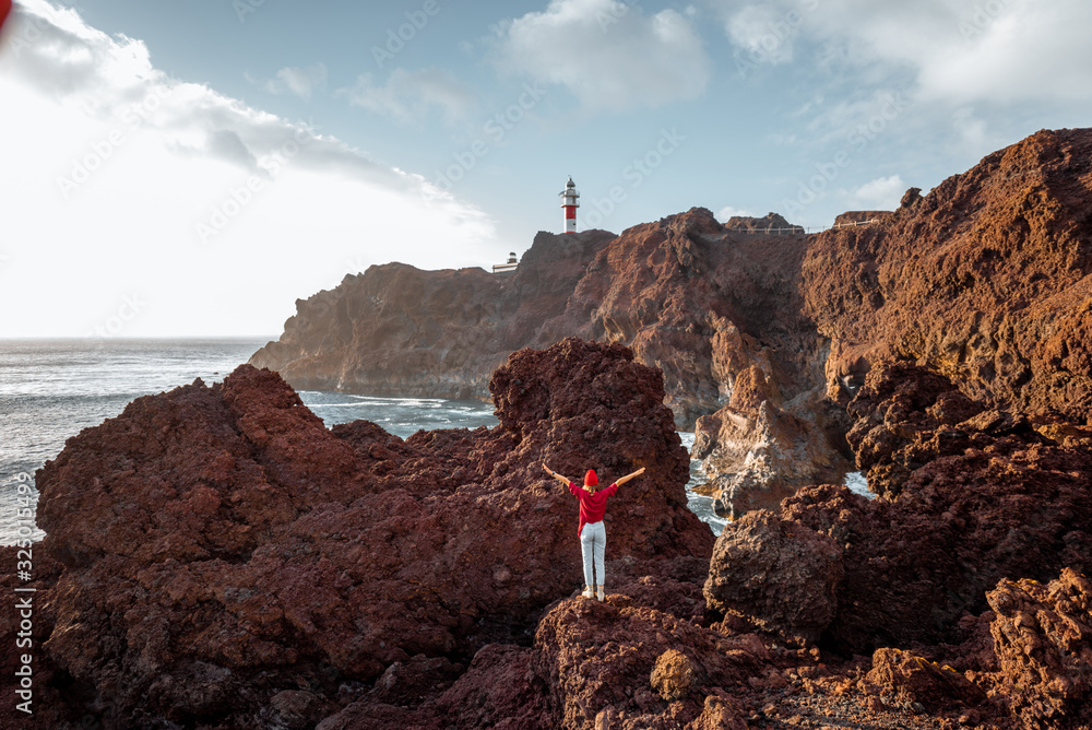 女人在岩石海岸欣赏美景，背景是灯塔，继续旅行