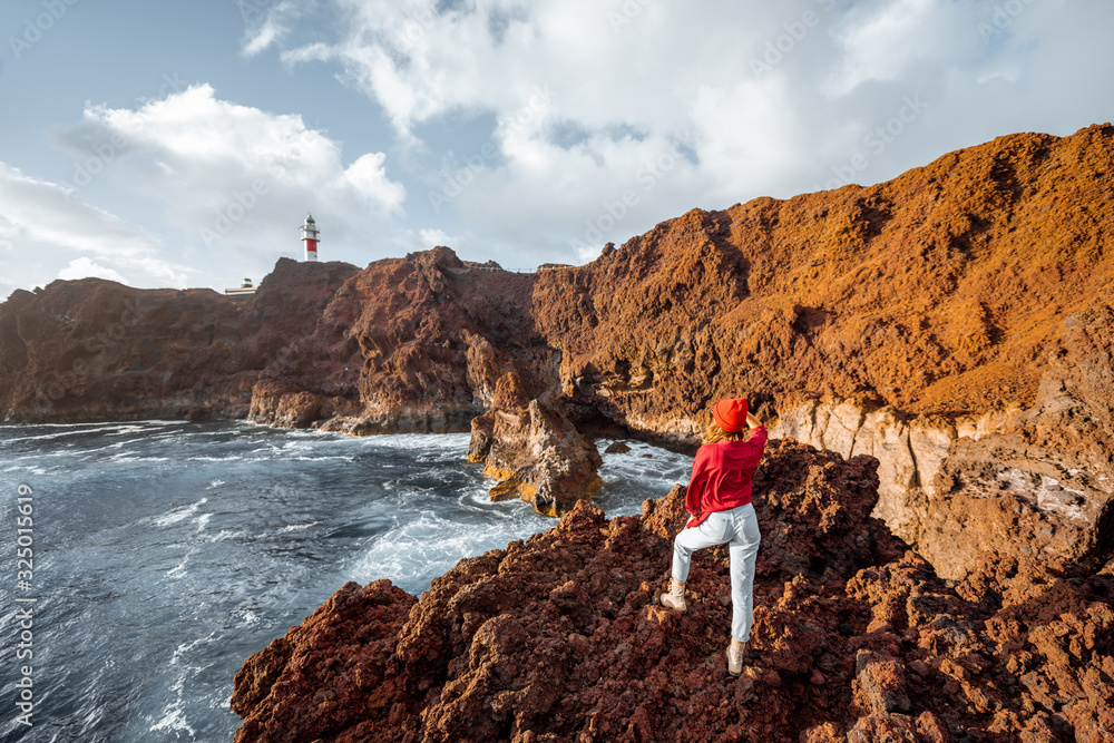 女人在岩石海岸欣赏美景，背景是灯塔，继续旅行