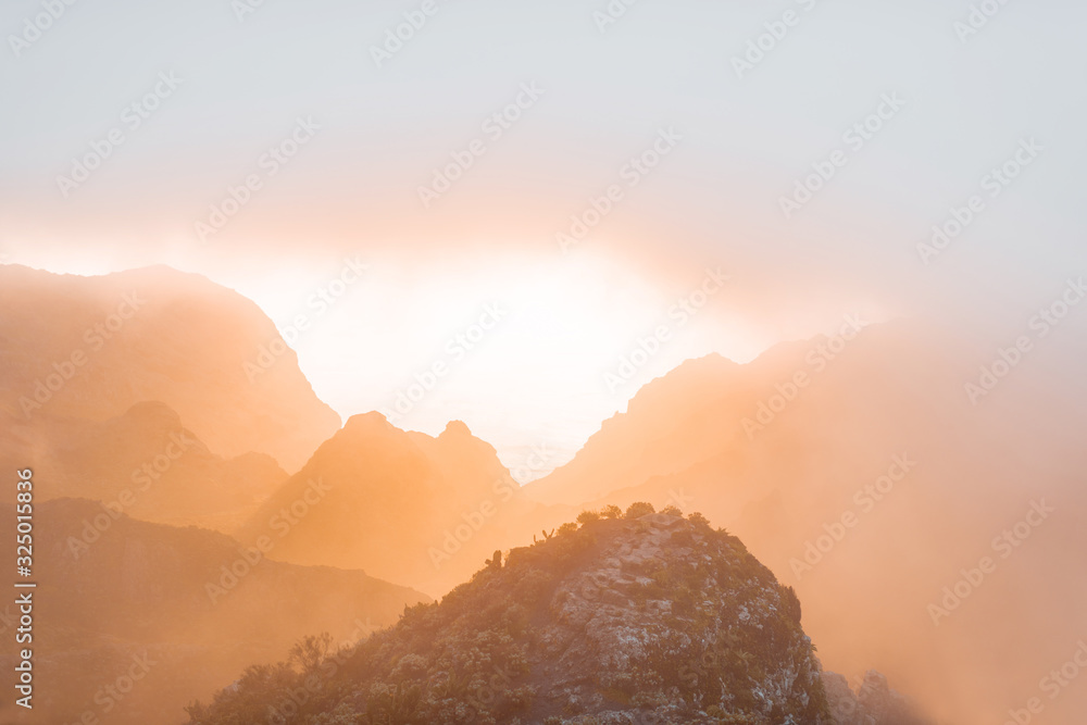 Breathtaking scenery on the mountain range under the clouds and ocean on the background during a sun