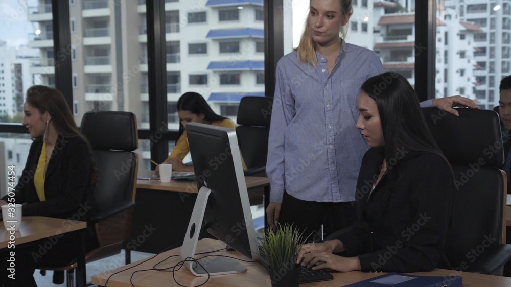 Young leader gives advice to young woman worker in modern office. Leadership and training concept.