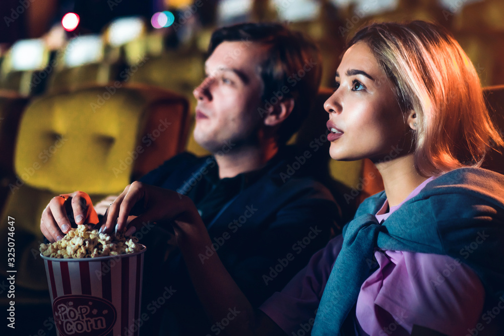 Caucasian lover enjoying to watch movie and eating popcorn together in the cinema