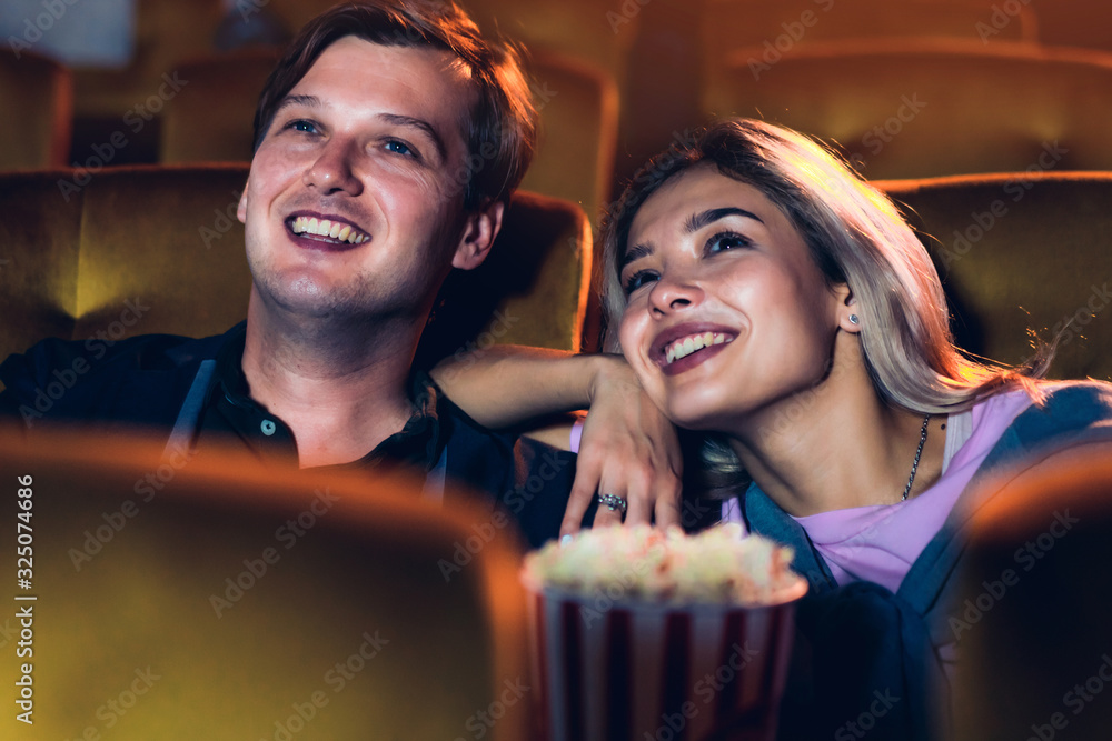 Caucasian lover enjoying to watch movie and eating popcorn together in the cinema