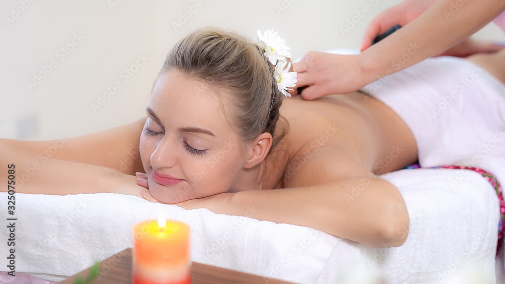 Relaxed woman getting back massage in luxury spa with professional massage therapist. Wellness, heal