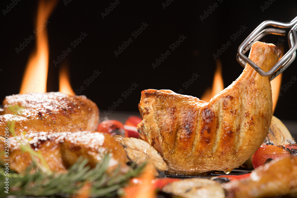 Grilled chicken thigh with various vegetables on the flaming grill