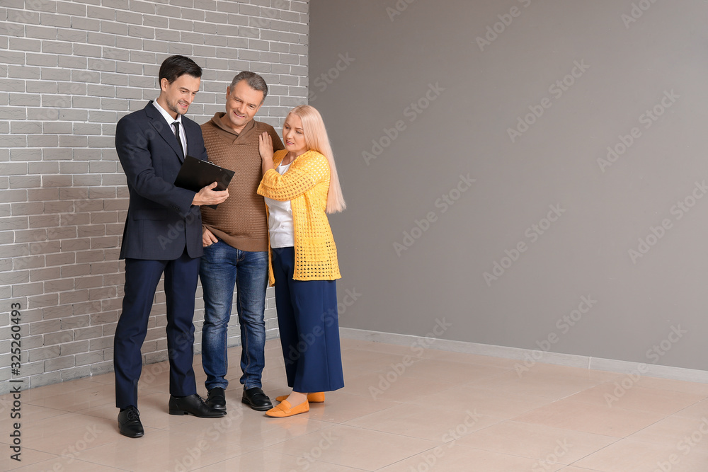 Male real estate agent working with mature couple indoors