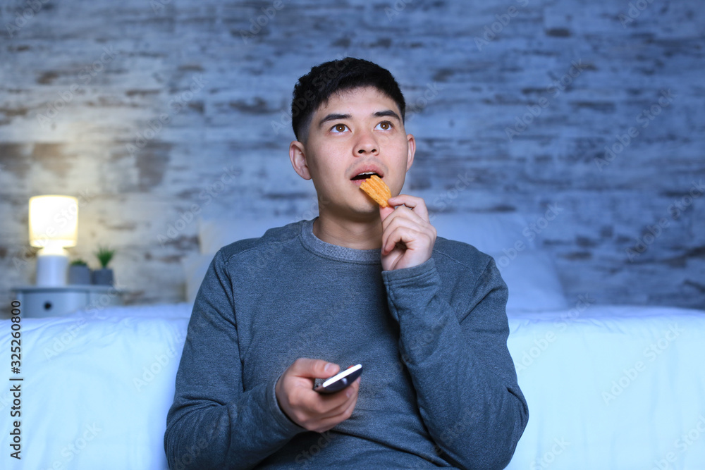 Asian man watching TV at home in evening