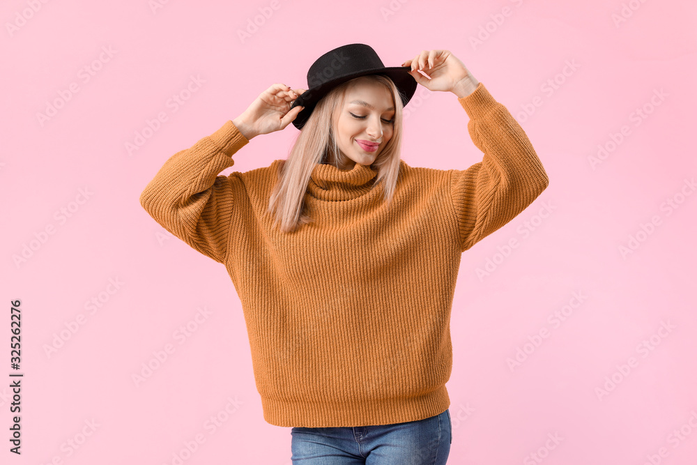 Young woman in warm sweater on color background