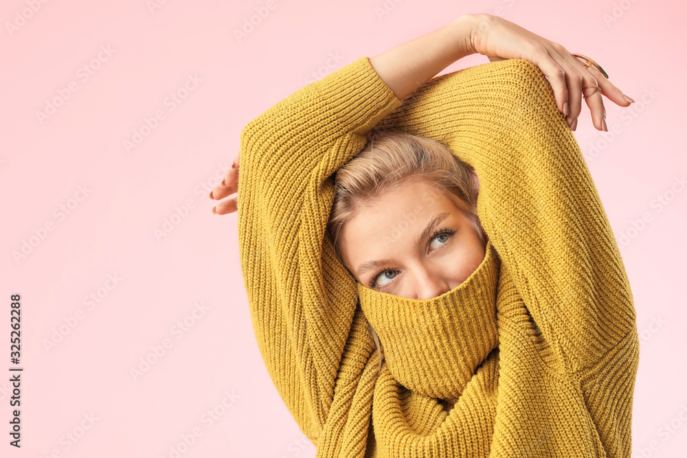 Young woman in warm sweater on color background