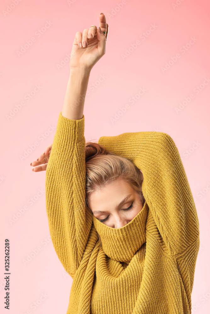 Young woman in warm sweater on color background