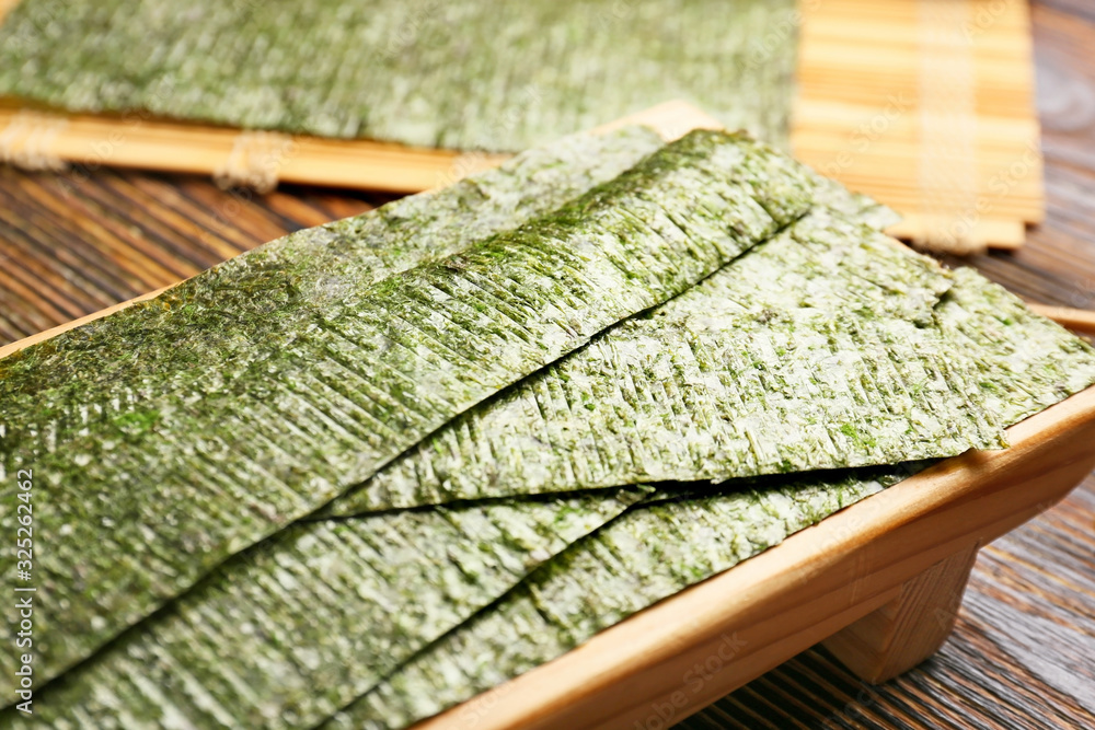 Board with tasty seaweed sheets on table, closeup