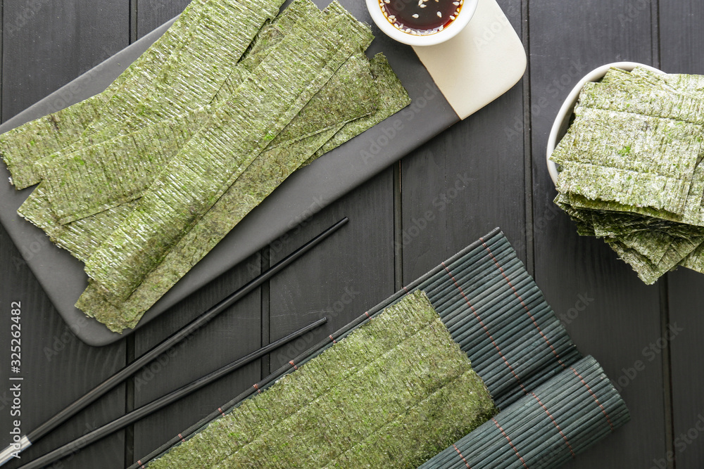 Tasty seaweed sheets and chopsticks on table