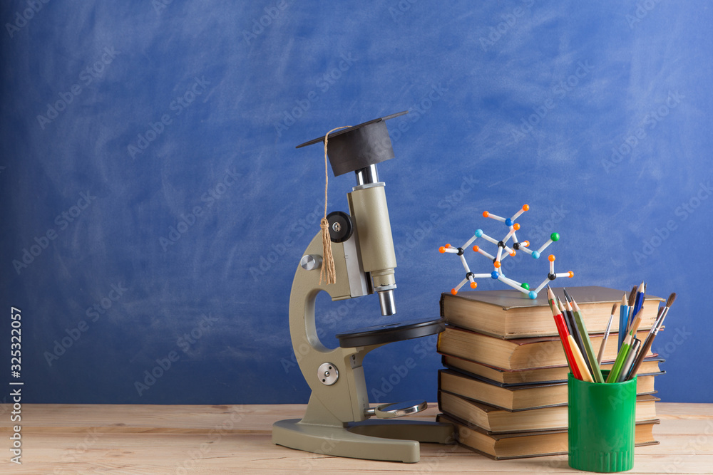 Education and sciences concept - books on the teacher desk in the auditorium, chalkboard on the back