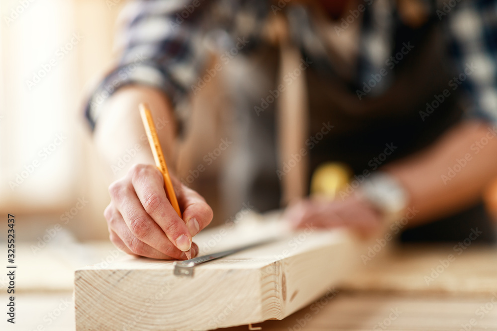 hands of master carpenter measure distance with pencil and tape measure