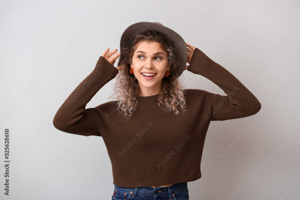 Beautiful young woman in warm sweater on light background