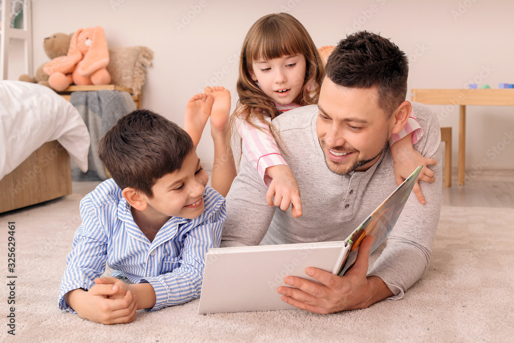 Father and his little children reading bedtime story at home