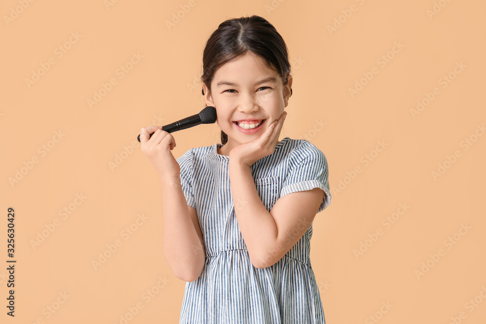 Cute little makeup artist on color background