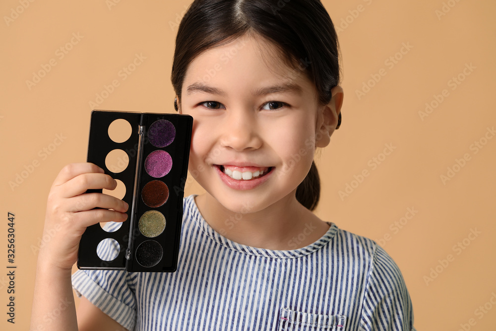 Cute little makeup artist on color background