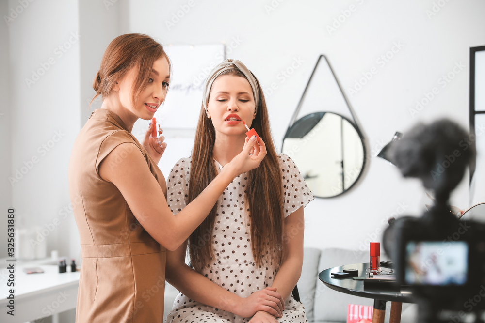 Young beauty blogger with model recording video at home