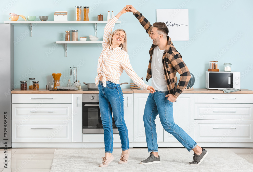 Happy dancing young couple in kitchen