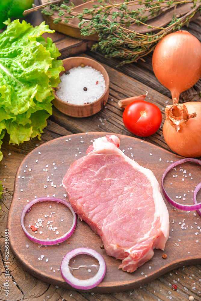 木质背景上有生猪肉、蔬菜和香料的木板