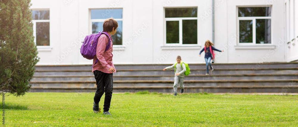 Children with rucksacks standing in the park near school