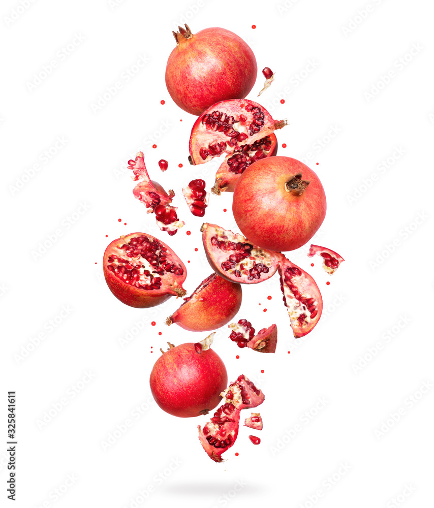 Whole and sliced ​​fresh pomegranate in the air, isolated on white background